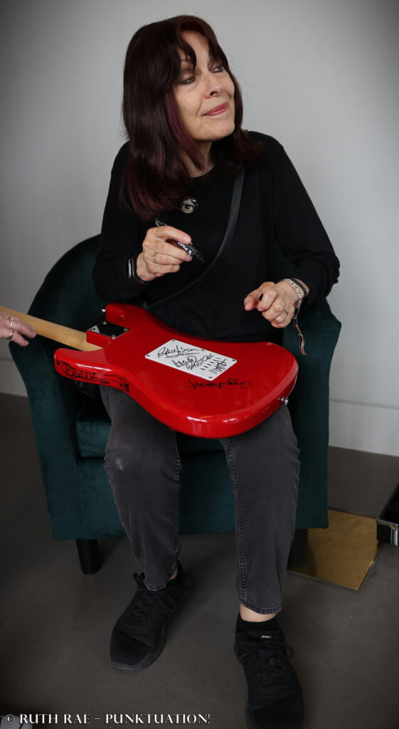 Gaye signs the guitar - Rebellion 2026 - photo © Ruth Rae